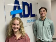 Young woman and young man standing in foreground with ADL Michigan sign in background